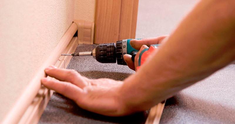 Fixing the baseboard with a screwdriver